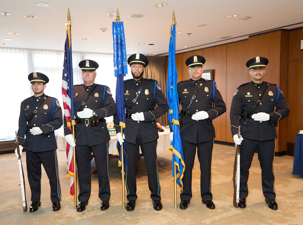 Five members of the U.S. Capitol Police Ceremonial Unit standing at attention in a ballroom