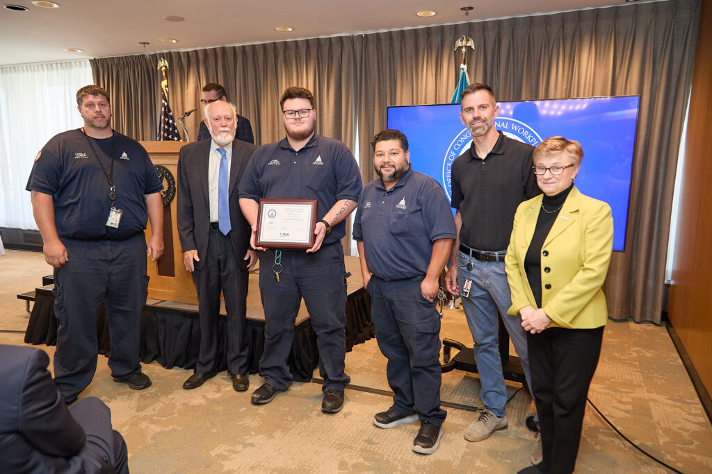 Four employees of the Architect of the Capitol pose to receive a framed award