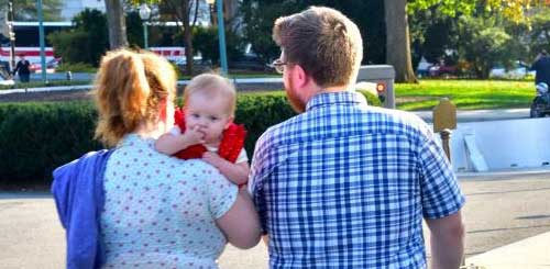 famiy of 3 walking in a park, woman holding the baby