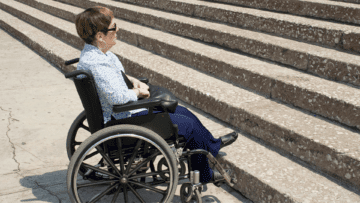 a person in a wheelchair outside, facing a set of stairs