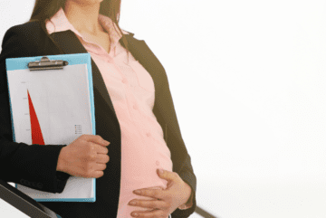 Pregnant woman holding her stomach and carrying a clipboard