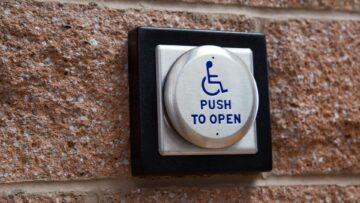 Automatic door opener button with a symbol of a person in a wheelchair and the words "Push To Open"