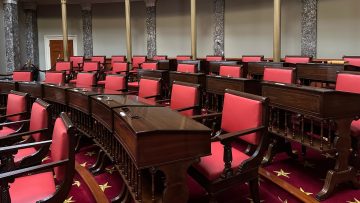 Rows of wooden desks and chairs with red upholstery in the old Senate chamber of the U.S. Capitol