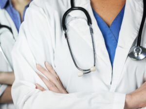 Two doctors wearing lab coats and stethoscopes standing with their arms folded across their chests
