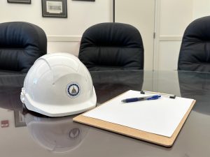A hard hat and clipboard rest on a conference table