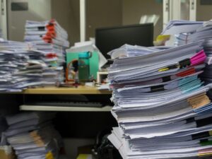 Work desk covered in precarious stacks of loose paper