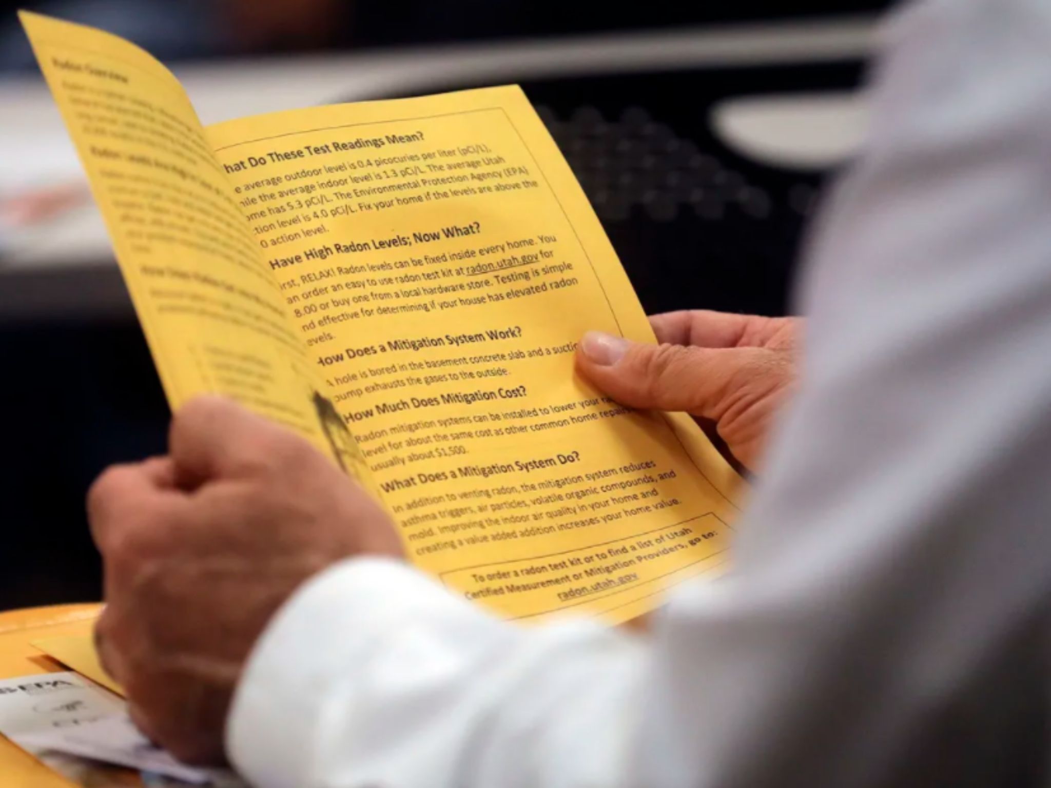 person reading a yellow brochure with warnings about Radon