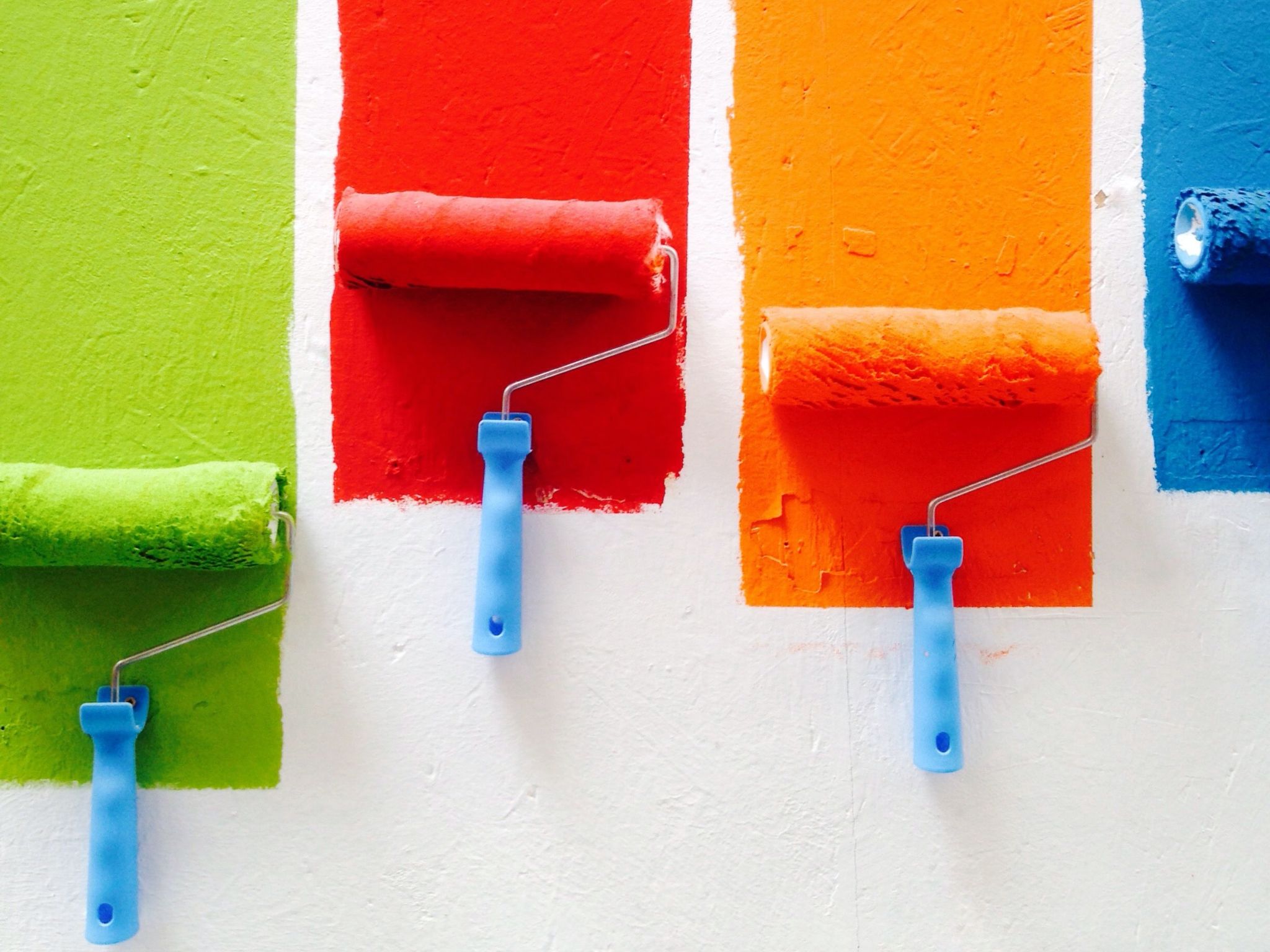 various colors of paint being brushed onto a wall
