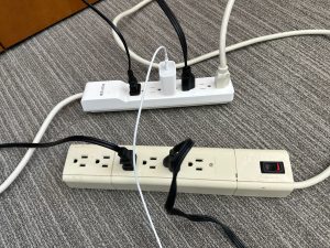 Two power strips with multiple cords plugged into them and one power strip plugged into the other