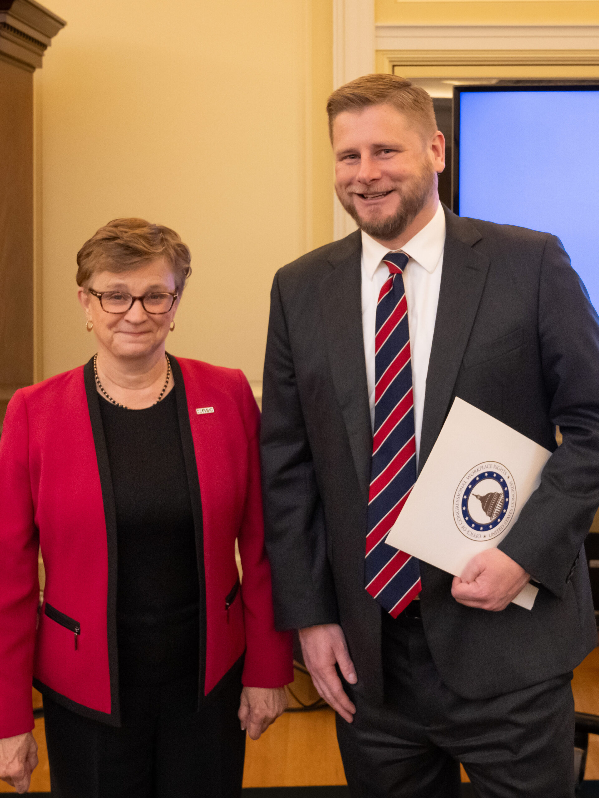 A woman on the left and a man on the right stand side by side, smiling