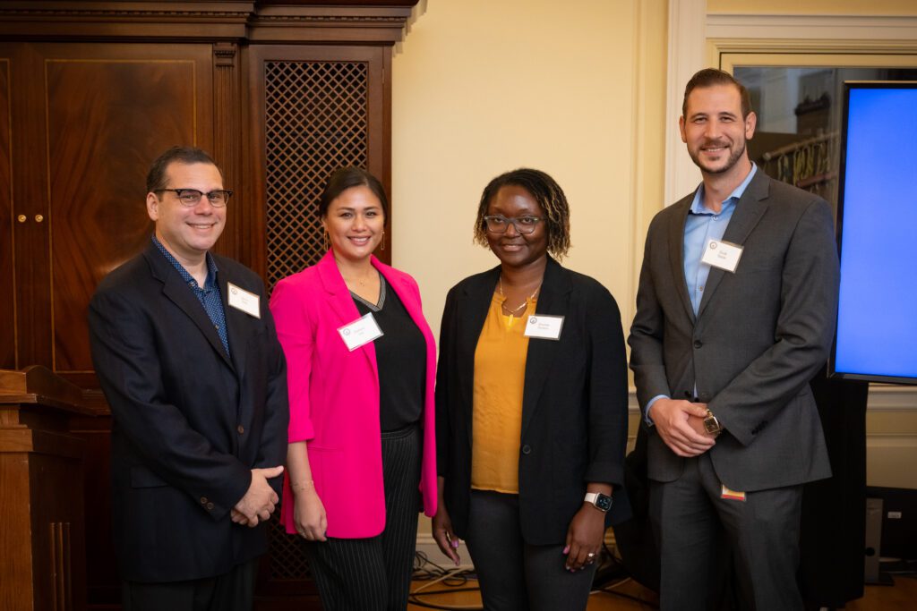 Four individuals in business attire pose for a photo